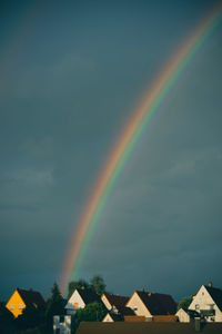 Rainbow over houses against sky