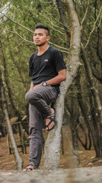 Young man standing on tree trunk in forest