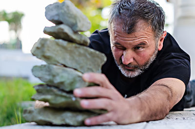 Mature man stacking rocks outdoors
