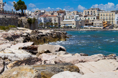 Buildings by sea against sky