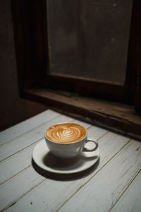 Latte art coffee on wooden table in coffee shop