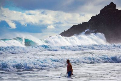 Rear view of man in sea against sky