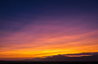 Scenic view of silhouette mountains against orange sky