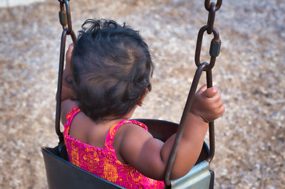 High angle view of girl sitting on swing at playground