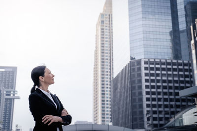 Full length of woman standing against skyscrapers