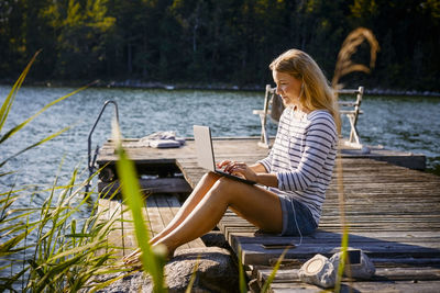 Woman sitting on deck chair by lake