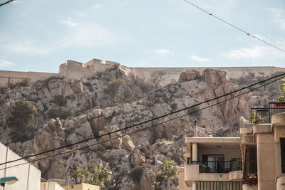 High section of houses by rocky mountains against sky