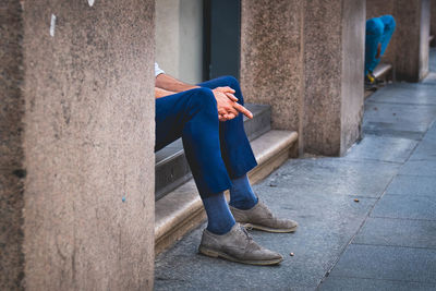 Low section of woman sitting on footpath