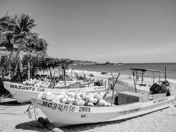 Fishing boats moored on beach against sky