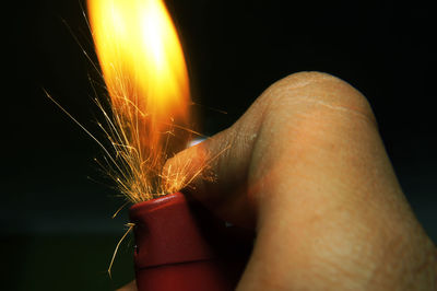 Close-up of hand holding sparkler against black background