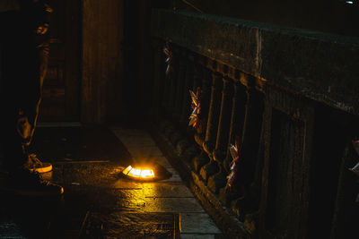 Low section of man standing by illuminated recessed light on floor by railing at night