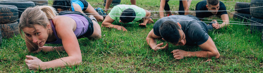 People crawling on grassy land under at boot camp