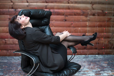A happy brunette woman is sitting workplace in a leather chair with 