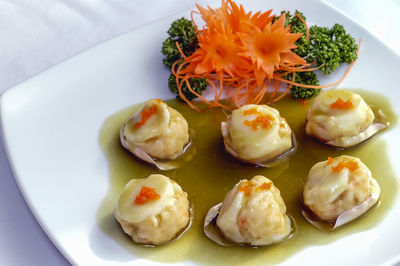 Steamed scallops with shrimp in a white dish on the table