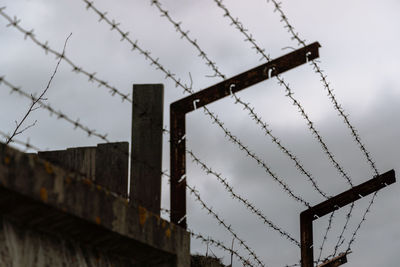 Low angle view of barbed wire fence against sky