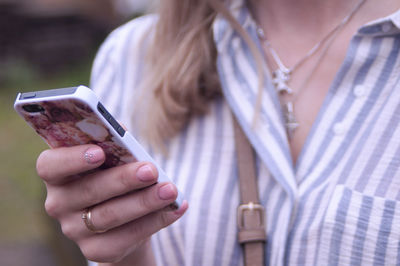 Midsection of woman using phone while standing outdoors