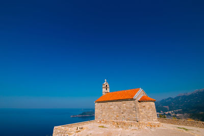 Building by sea against clear blue sky