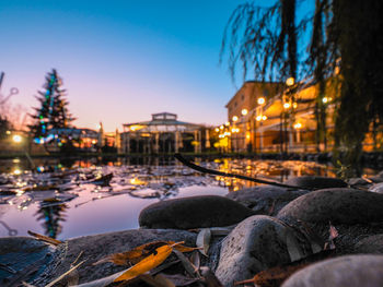 Surface level of river amidst illuminated trees against sky during winter