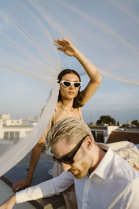 Young woman and man sitting under veil on rooftop