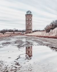 Building by lake against sky during winter