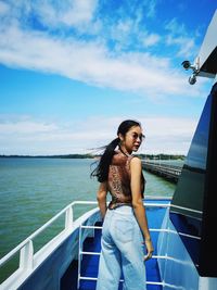 Portrait of young woman standing in nautical vessel at sea