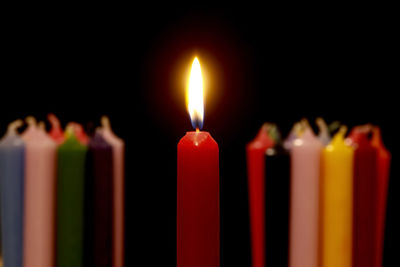 Close-up of candle burning against black background