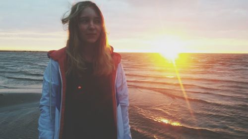 Portrait of woman standing at beach during sunset
