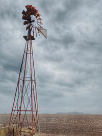 Low angle view of windmill on field against sky