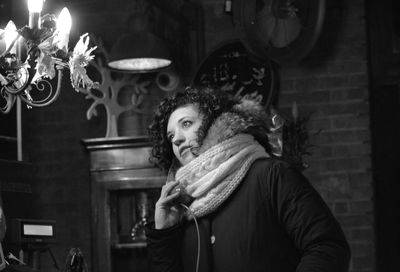 Woman looking at illuminated lighting equipment in darkroom during winter