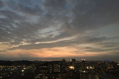 Illuminated cityscape against sky at sunset