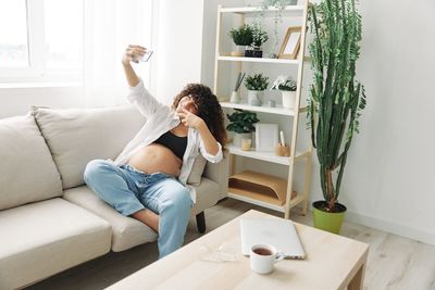 Side view of woman sitting on sofa at home