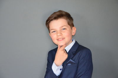 Portrait of smiling boy against gray background