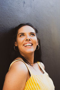Portrait of a smiling young woman standing against wall