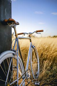 Bicycle on golden field against sky during sunset