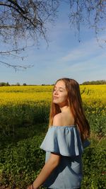 Teenage girl on field against sky