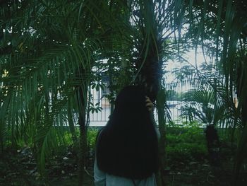 Woman standing on tree trunk against plants