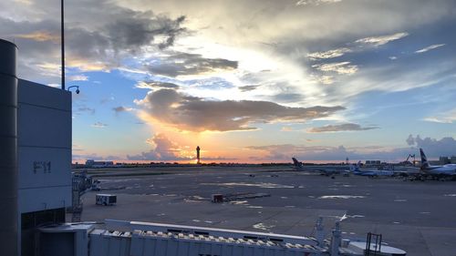 Airplane on airport runway against sky during sunset