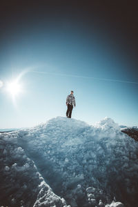 Low angle view of person standing on snow covered mountain