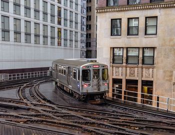 Tram on railroad track against buildings