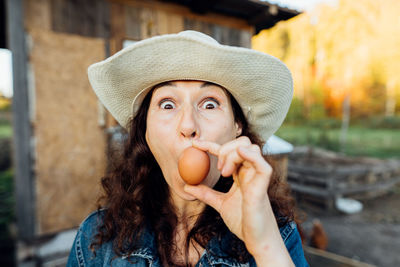 Funny woman farmer in denim with a fresh egg, making a funny face