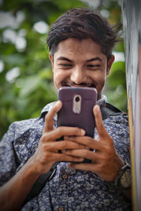 Low angle view of man using phone while standing outdoors