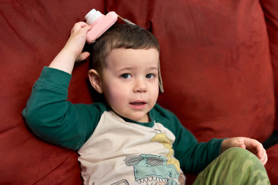 Cute toddler playing with a toy camera while watching tv at home