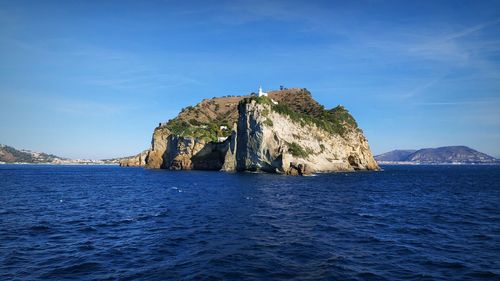 Scenic view of rock formation in sea against blue sky