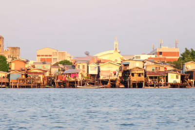 Buildings by sea against clear sky