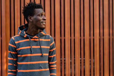 Portrait of young man looking away against wall