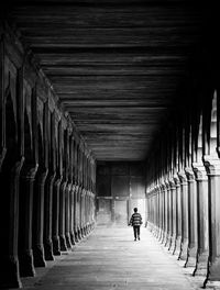 Rear view of woman walking on footpath in old building