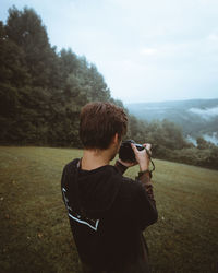 Rear view of man photographing through camera