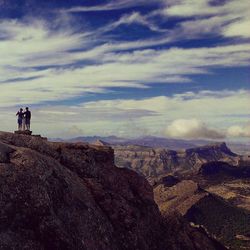 Person standing on mountain against cloudy sky