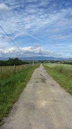 Road amidst field against sky