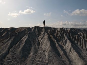 Boy standing on cliff against sky